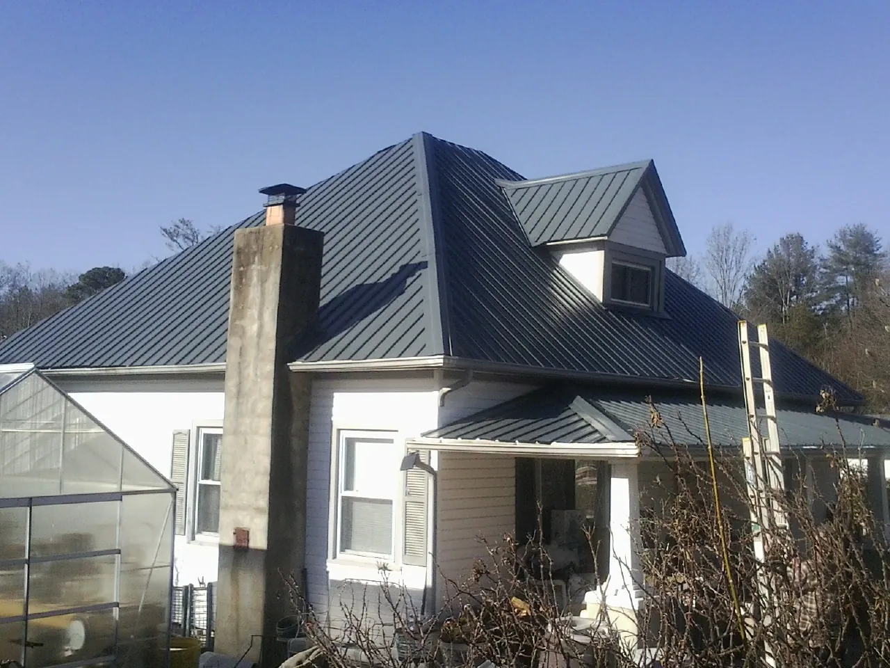 Dark blue standing seam metal roof on a white farmhouse with dormer — Slate & Tile Roof Repair by Roofing Brothers in West Manchester