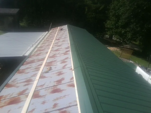 Old rusted panels beside newly installed green metal roofing — Wind Damage Roof Repair by Roofing Brothers in West Manchester