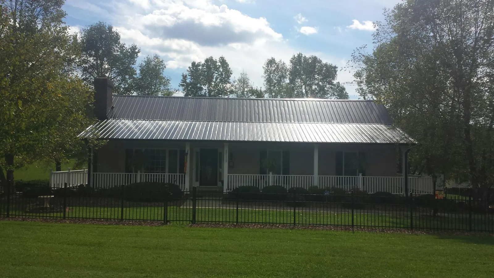 Gray metal roof on a brick ranch with a full width front porch — Gutter Guard Installation work by our crew in West Manchester