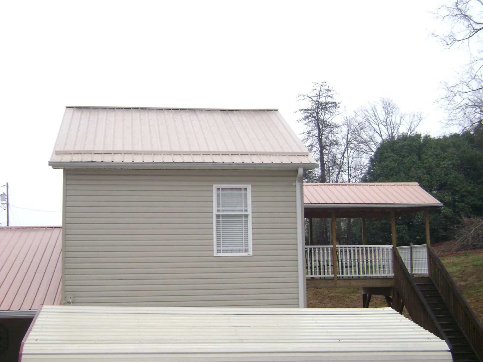 Tan metal roofs on a two story addition and attached porch, from a Roof Replacement job in West Manchester