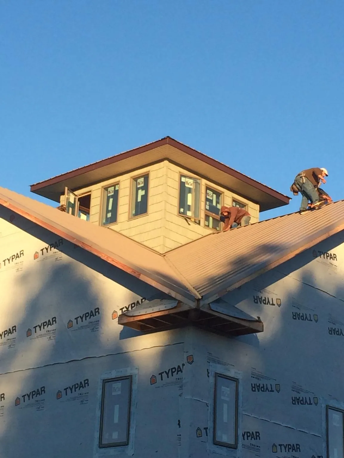 Roofers working around a rooftop cupola on a new metal roof at sunset — Roof Waterproofing in West Manchester by Roofing Brothers